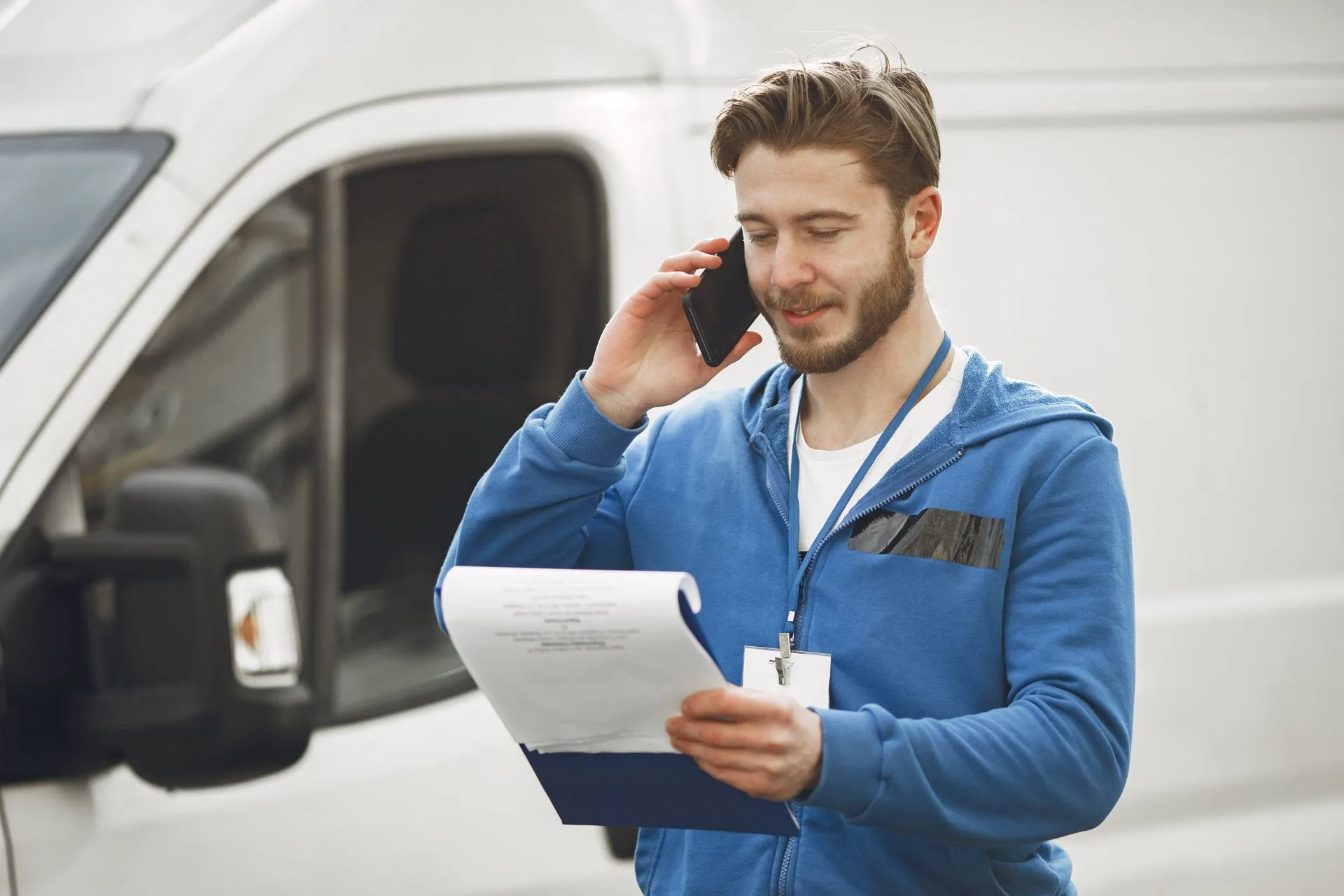 Driver on the phone beside a van, checking a job